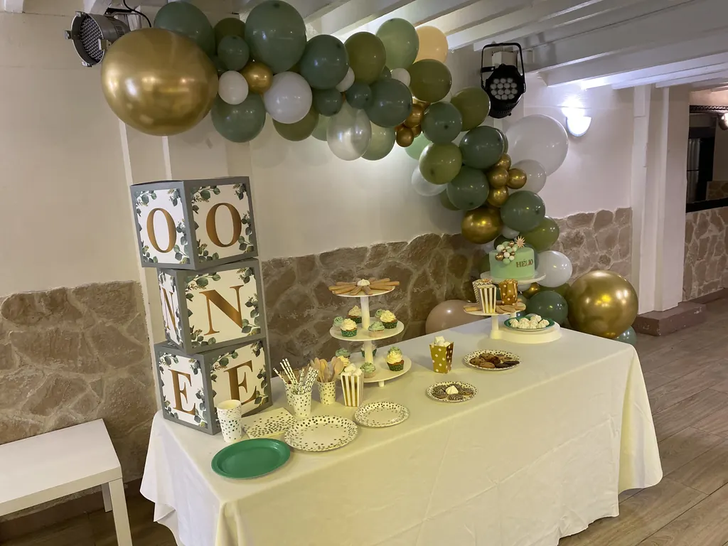 Buffet de premier anniversaire avec arche de ballons vert sauge et or