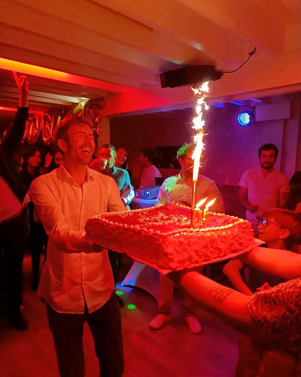 Gâteau d'anniversaire avec bougies fontaines au milieu des invités